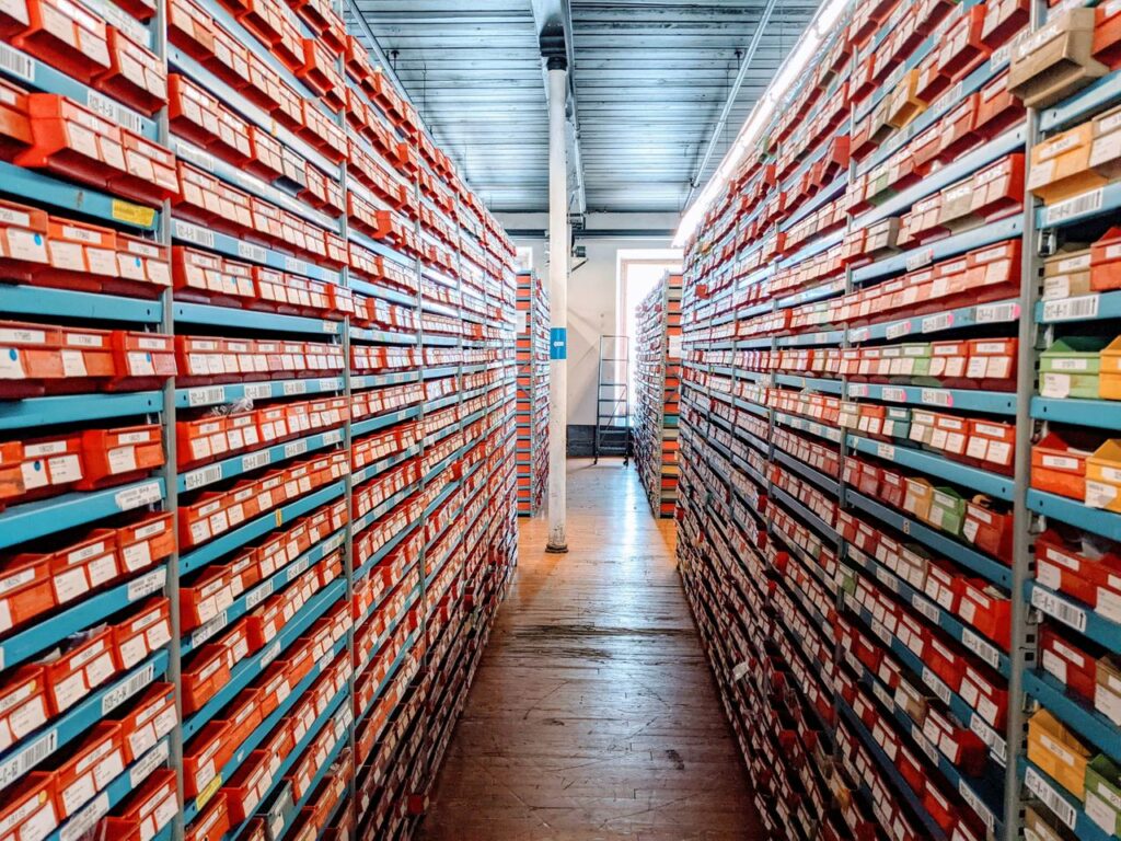 The Art of Drawing Readers In: Your attractive post title goes here A well-organized warehouse aisle filled with red shoe boxes on shelves, showcasing efficient inventory storage.